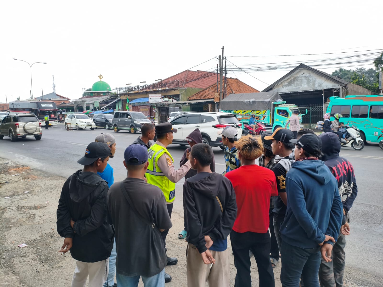 Personel Pos PAM Jomin Polres Karawang mengatur arus lalu lintas dan menertibkan Pak Ogah di kawasan turunan Flyover Jomin saat Operasi Ketupat Lodaya 2026.
